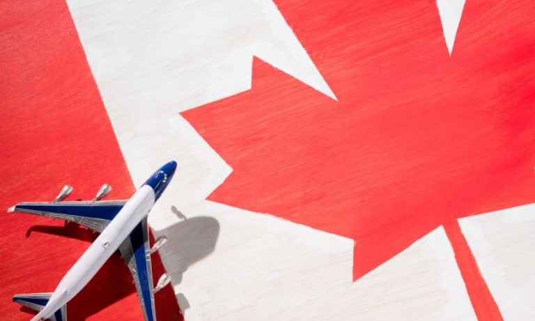 A small airplane flying over a large Canadian flag